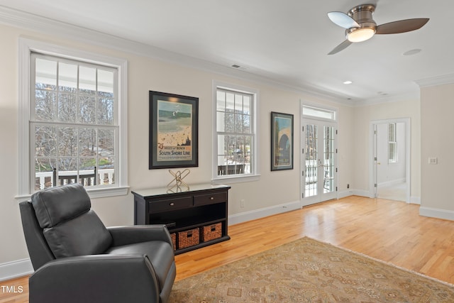 living area featuring light wood-style flooring, visible vents, baseboards, and crown molding