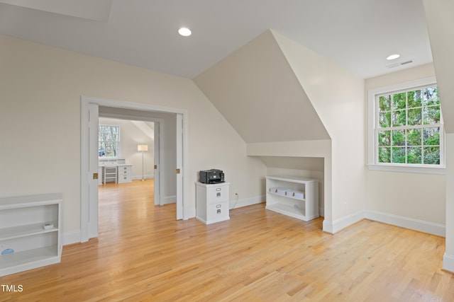 additional living space with recessed lighting, visible vents, light wood-style floors, vaulted ceiling, and baseboards