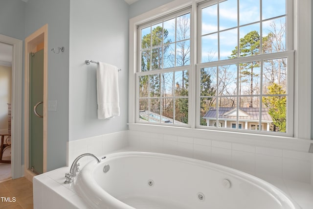 bathroom with a tub with jets, a stall shower, and tile patterned floors