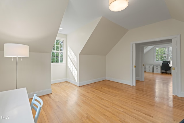 additional living space featuring baseboards, lofted ceiling, and light wood-style floors