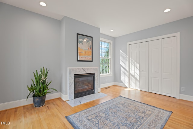 living area with a premium fireplace, recessed lighting, wood finished floors, and baseboards