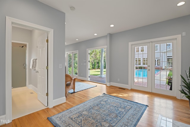 interior space with light wood finished floors, recessed lighting, visible vents, and french doors