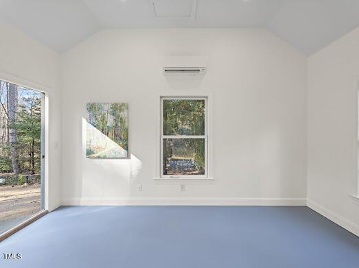 unfurnished room with lofted ceiling, finished concrete flooring, baseboards, and a wall mounted air conditioner