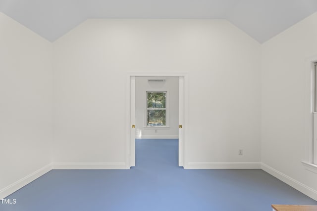 empty room with lofted ceiling, concrete floors, and baseboards