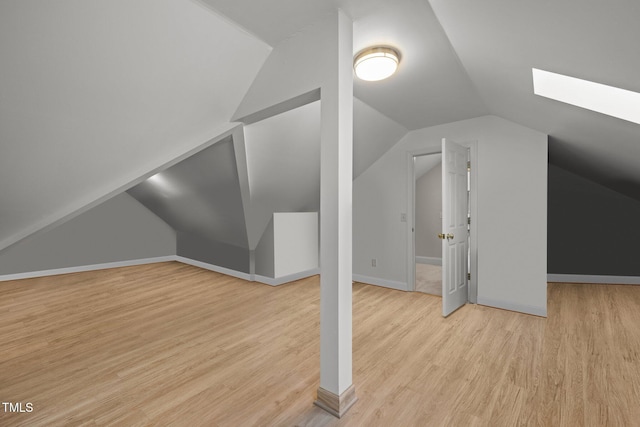 additional living space with lofted ceiling with skylight, wood finished floors, and baseboards