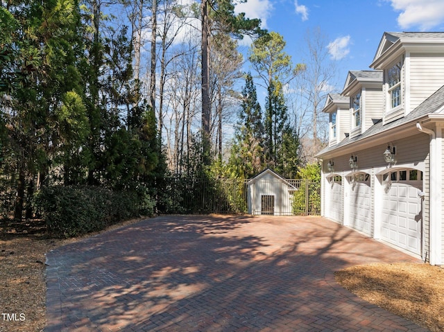 view of home's exterior with a garage, decorative driveway, and an outbuilding