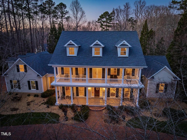 view of front of home with a shingled roof, a patio area, and a balcony