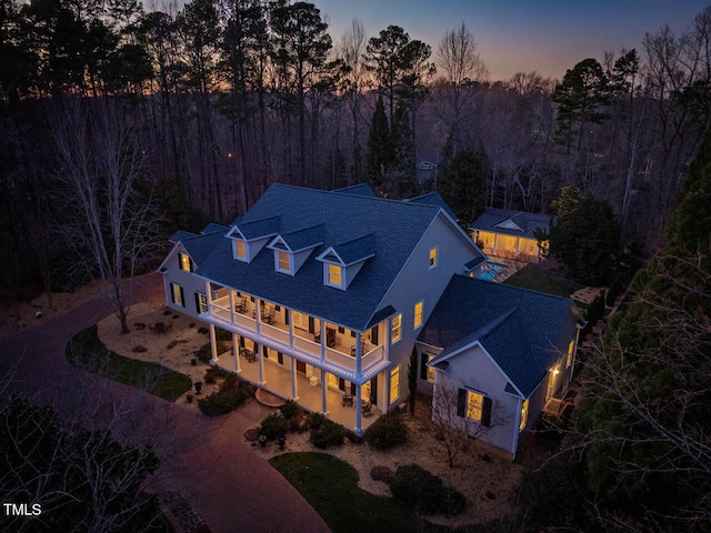 aerial view at dusk featuring a forest view