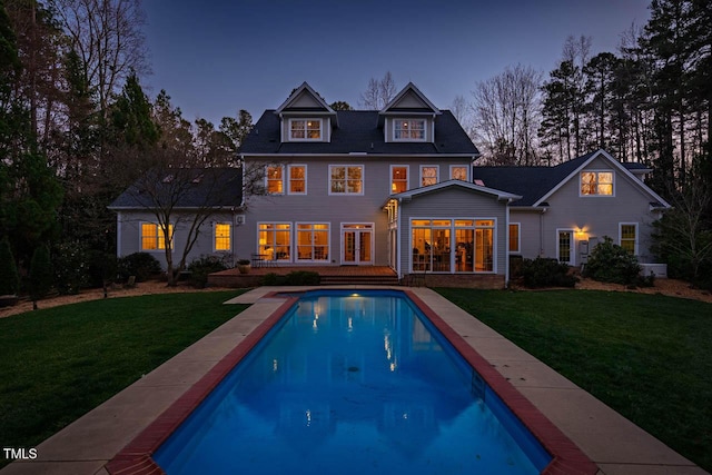 rear view of house with a yard, an outdoor pool, and a deck