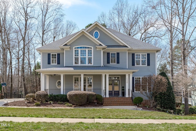 view of front of home featuring covered porch, roof with shingles, and a front lawn