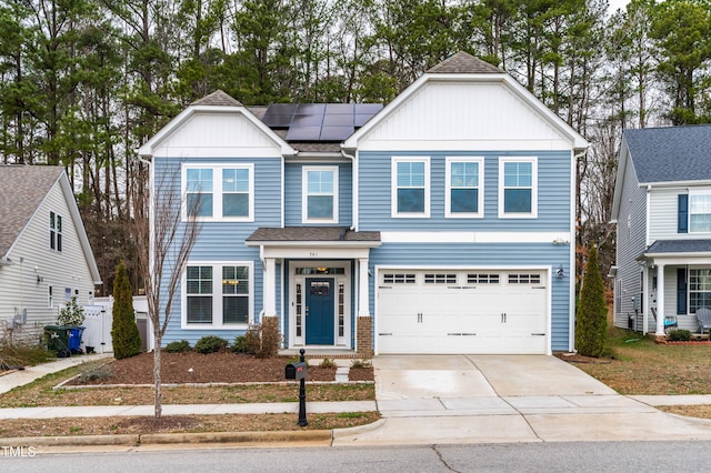 view of front of home with board and batten siding, concrete driveway, roof with shingles, a garage, and solar panels