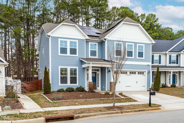 townhome / multi-family property featuring solar panels, board and batten siding, concrete driveway, and fence