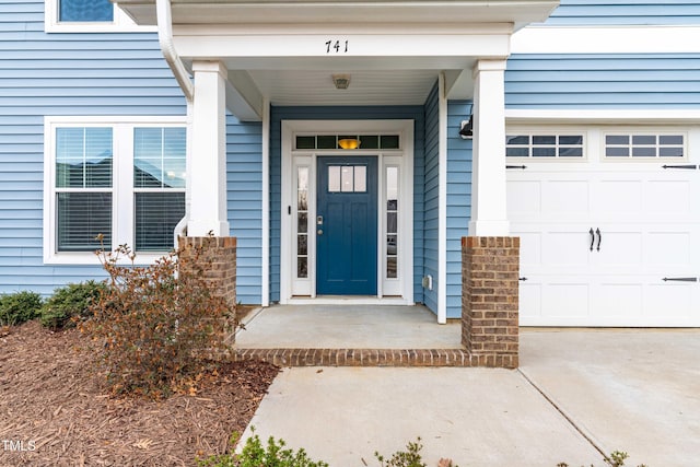 view of exterior entry featuring an attached garage and driveway