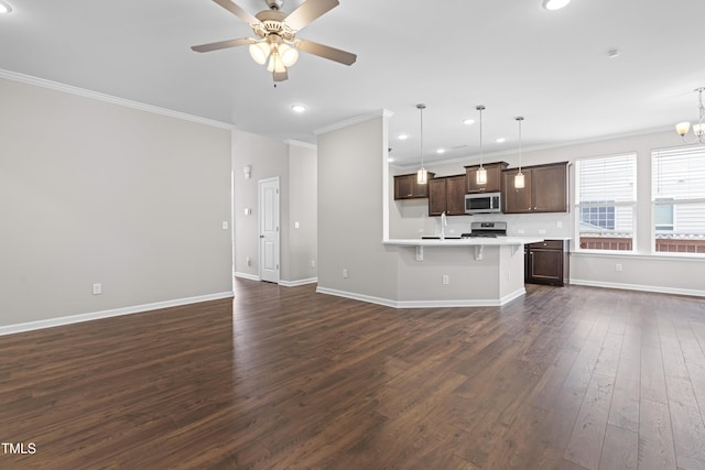 kitchen with dark wood finished floors, open floor plan, ceiling fan with notable chandelier, and appliances with stainless steel finishes