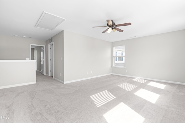 empty room featuring visible vents, baseboards, light colored carpet, attic access, and a ceiling fan