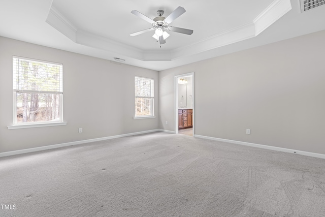 empty room featuring visible vents, a raised ceiling, ornamental molding, and a ceiling fan