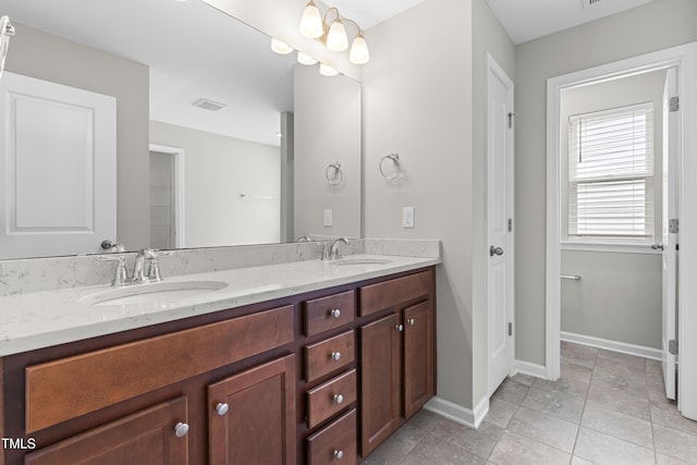 bathroom with a sink, visible vents, baseboards, and double vanity