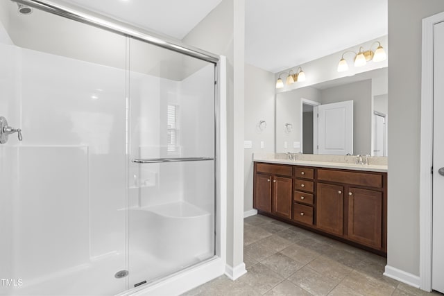 bathroom featuring double vanity, baseboards, a stall shower, and a sink