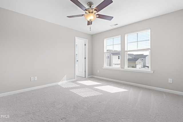 carpeted spare room with visible vents, baseboards, and ceiling fan