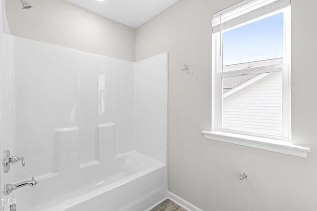 bathroom featuring tub / shower combination and baseboards