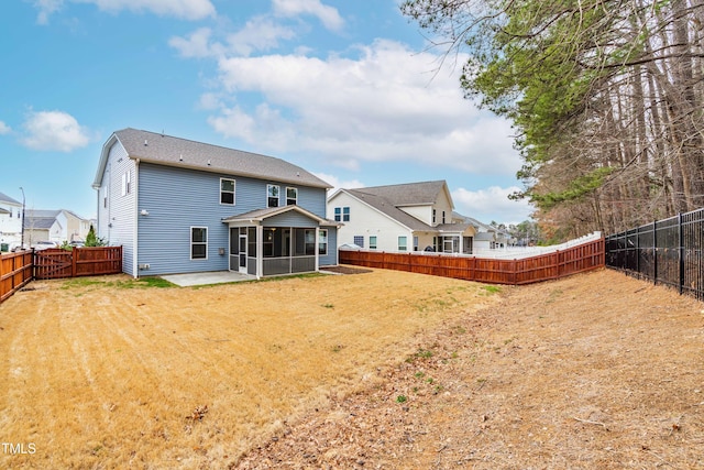 back of house featuring a patio area, a lawn, a fenced backyard, and a sunroom