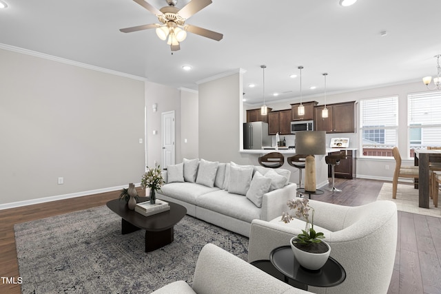 living room with ceiling fan with notable chandelier, dark wood-style floors, recessed lighting, crown molding, and baseboards