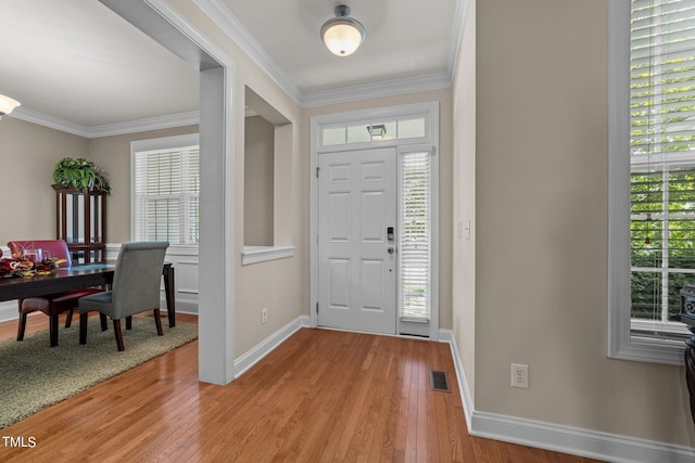 foyer entrance featuring visible vents, ornamental molding, light wood-style flooring, and baseboards