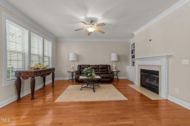 living area featuring crown molding, a premium fireplace, baseboards, and wood finished floors