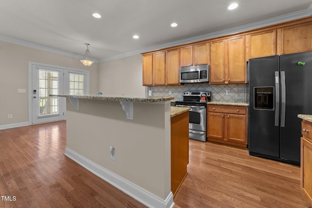 kitchen with stainless steel appliances, ornamental molding, brown cabinetry, and light wood-style flooring