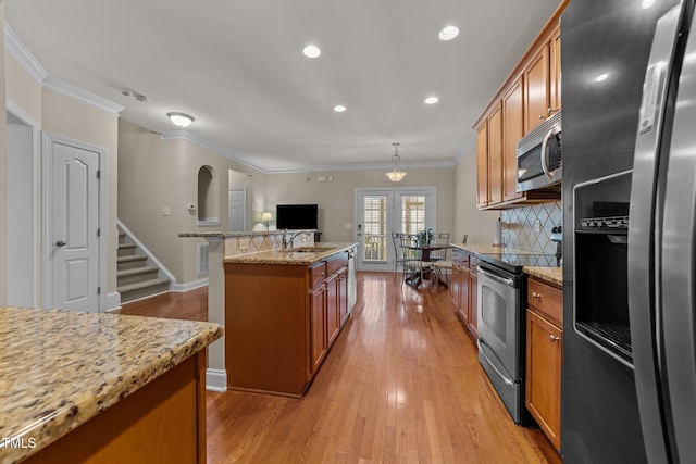 kitchen with brown cabinets, ornamental molding, and stainless steel appliances