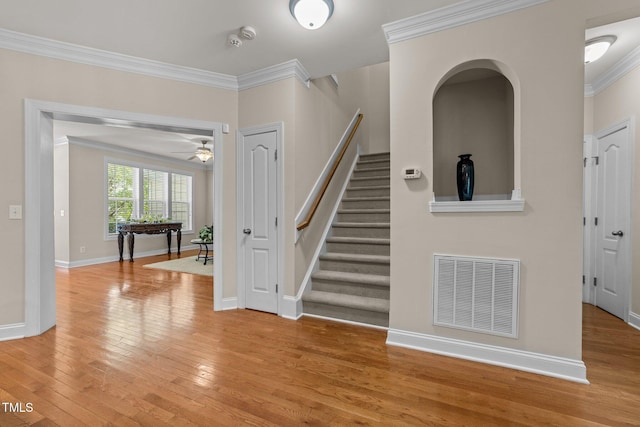 interior space featuring baseboards, visible vents, crown molding, and light wood finished floors