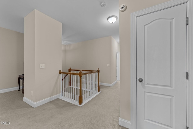 corridor with baseboards, light carpet, and an upstairs landing