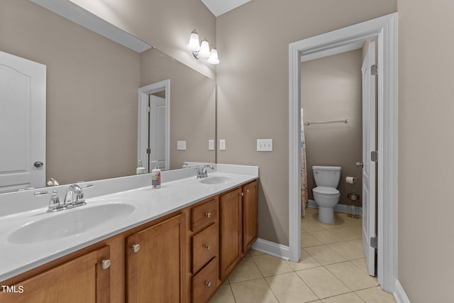 bathroom featuring double vanity, tile patterned flooring, toilet, and a sink