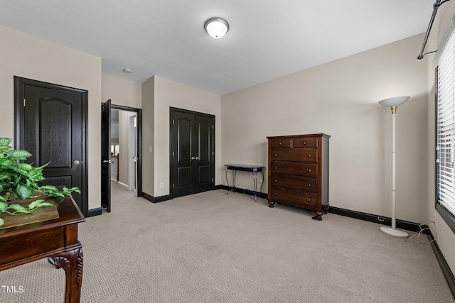 bedroom with baseboards, a closet, and light colored carpet