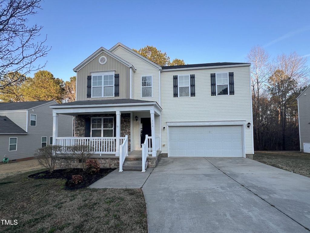 traditional-style home with covered porch, concrete driveway, board and batten siding, and an attached garage