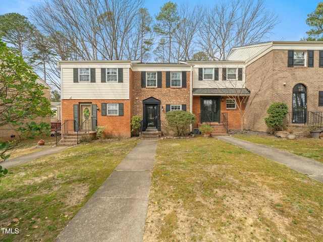 multi unit property with a front yard and brick siding