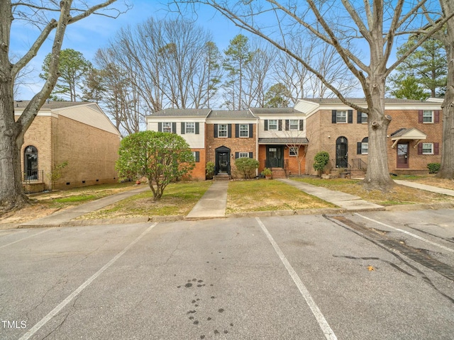 view of property with uncovered parking and brick siding