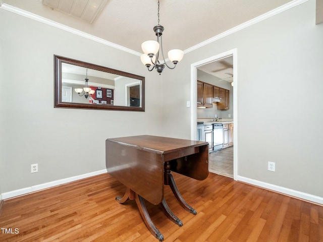 dining area featuring visible vents, baseboards, light wood-style floors, ornamental molding, and an inviting chandelier