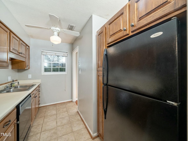 kitchen with light countertops, visible vents, freestanding refrigerator, a sink, and dishwashing machine