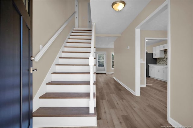 stairway with baseboards and wood finished floors