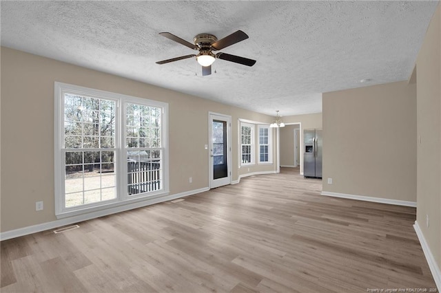 unfurnished living room featuring visible vents, light wood-style flooring, baseboards, and ceiling fan with notable chandelier