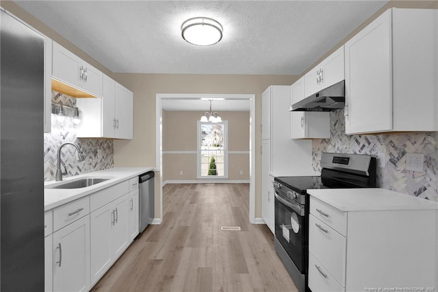 kitchen featuring white cabinets, stainless steel appliances, light countertops, under cabinet range hood, and a sink