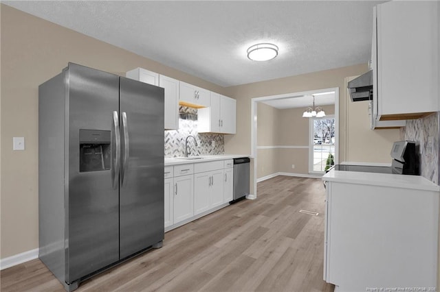 kitchen with stainless steel appliances, tasteful backsplash, a sink, and white cabinetry