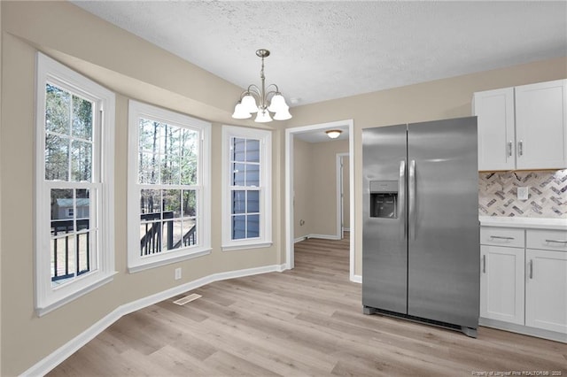 kitchen featuring pendant lighting, baseboards, stainless steel fridge, and light wood finished floors