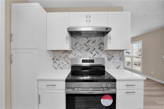 kitchen with tasteful backsplash, under cabinet range hood, stainless steel electric range oven, and light countertops