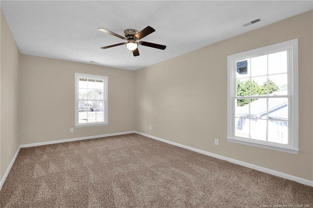 carpeted spare room with visible vents, ceiling fan, and baseboards