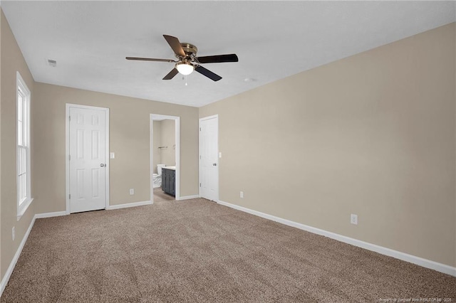 unfurnished bedroom featuring ceiling fan, connected bathroom, visible vents, baseboards, and carpet