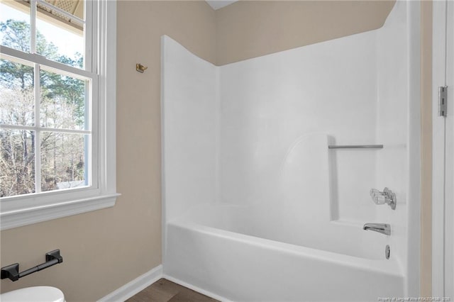 full bath with toilet, bathtub / shower combination, and baseboards