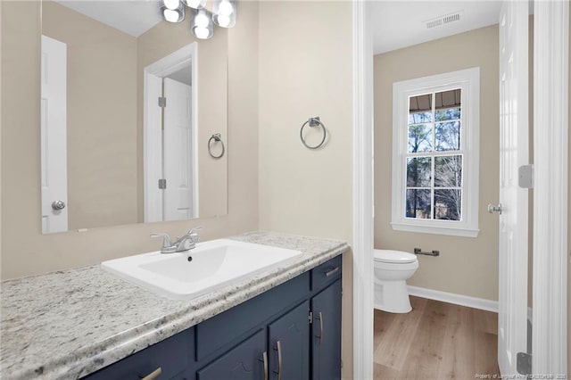 bathroom with baseboards, visible vents, toilet, wood finished floors, and vanity