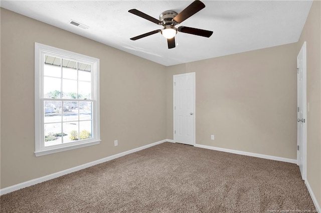 unfurnished room with carpet floors, baseboards, visible vents, and a ceiling fan